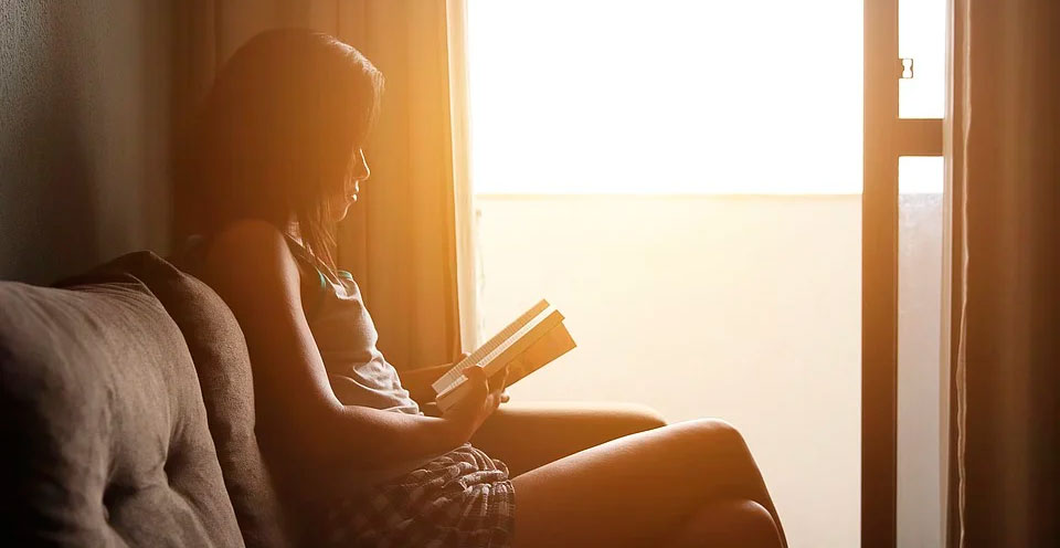 imagem de uma mulher sentada lendo um livro 